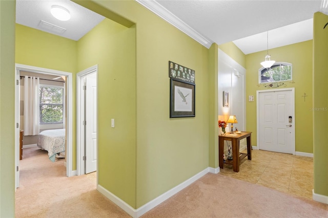 carpeted foyer entrance with a textured ceiling and ornamental molding