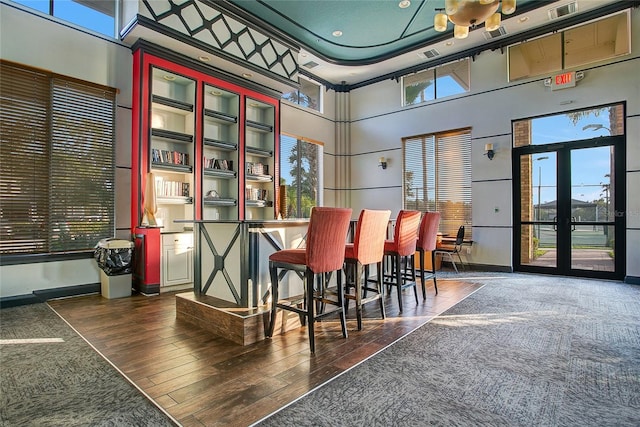 bar featuring dark wood-type flooring and a towering ceiling