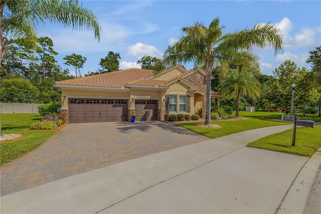 mediterranean / spanish home with a garage and a front lawn