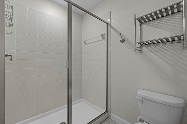 bathroom featuring a shower with shower door and toilet