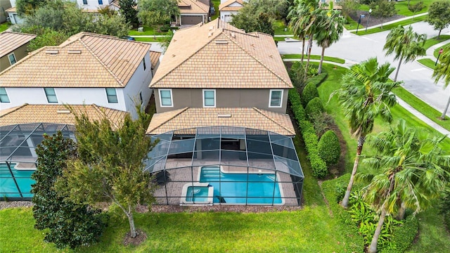 back of house with a lanai, a residential view, a tile roof, stucco siding, and an outdoor pool