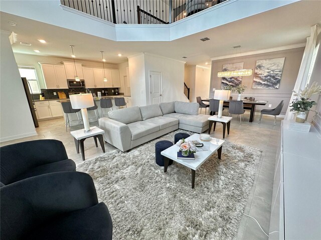 living room featuring crown molding, a towering ceiling, and light tile patterned floors