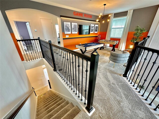 staircase featuring pool table, carpet flooring, and a notable chandelier