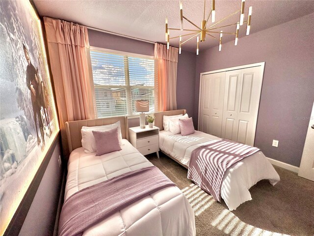 carpeted bedroom with a textured ceiling, an inviting chandelier, and a closet