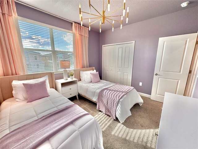 bedroom with a textured ceiling, carpet floors, an inviting chandelier, and a closet