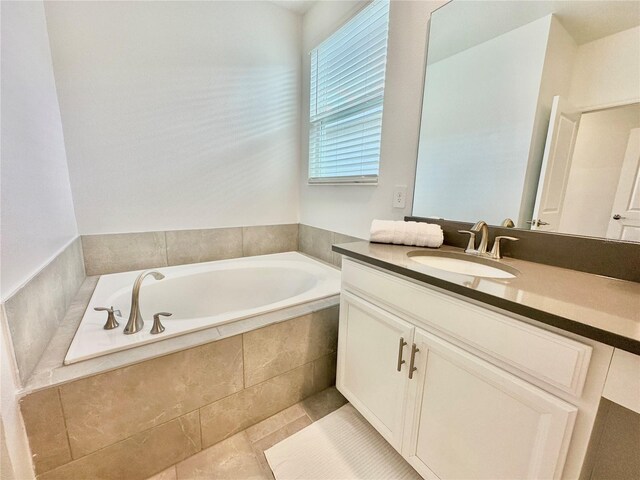 bathroom with vanity, a relaxing tiled tub, and tile patterned flooring