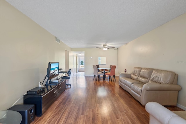 living room featuring ceiling fan, a textured ceiling, and wood-type flooring