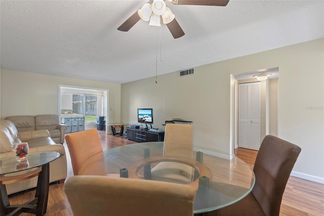 dining space featuring ceiling fan, a textured ceiling, and light wood-type flooring