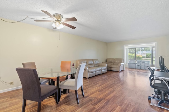 dining space featuring a textured ceiling, wood-type flooring, and ceiling fan