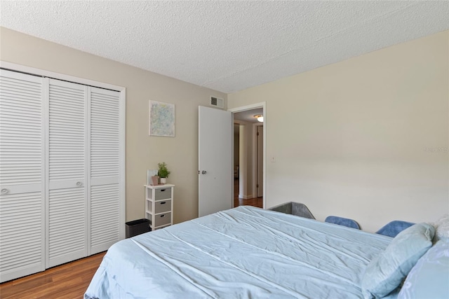 bedroom featuring a closet, hardwood / wood-style flooring, and a textured ceiling