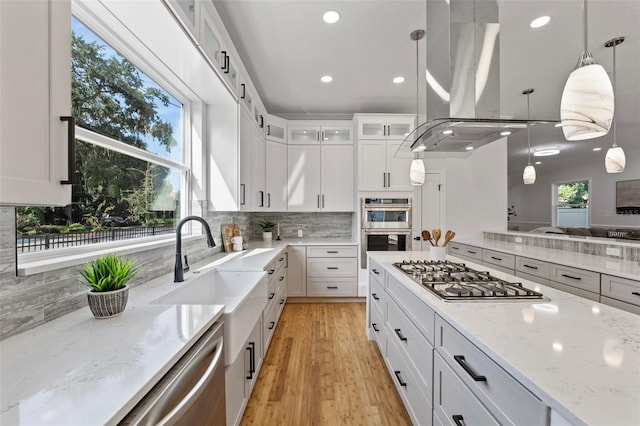 kitchen featuring pendant lighting, white cabinets, island exhaust hood, and appliances with stainless steel finishes