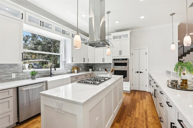 kitchen with a center island, white cabinets, island exhaust hood, hanging light fixtures, and appliances with stainless steel finishes