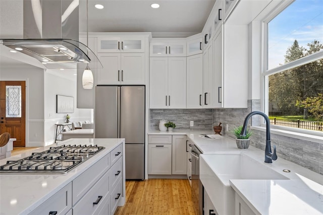 kitchen featuring sink, white cabinets, island exhaust hood, light hardwood / wood-style flooring, and appliances with stainless steel finishes