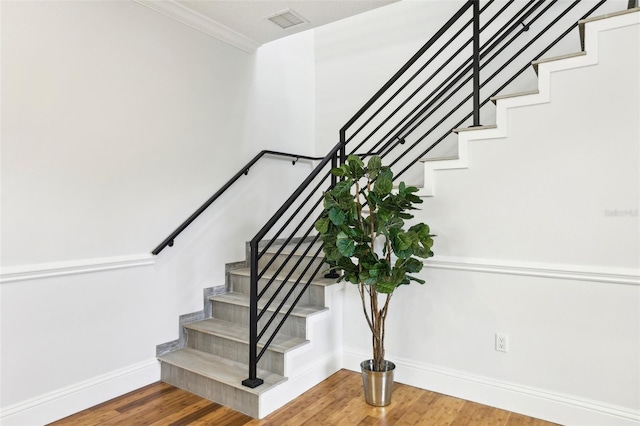 staircase featuring wood-type flooring and crown molding