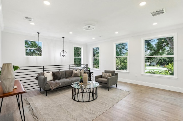 living room with a healthy amount of sunlight, crown molding, and light hardwood / wood-style flooring