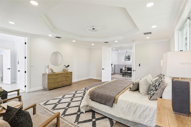 bedroom featuring light wood-type flooring, a raised ceiling, and crown molding