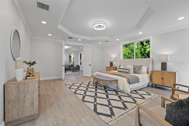 bedroom featuring light wood-type flooring, a tray ceiling, and crown molding