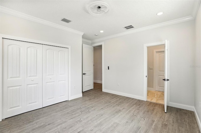 unfurnished bedroom featuring light wood-type flooring, ornamental molding, and a closet