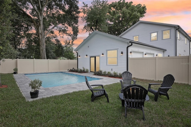 pool at dusk featuring a lawn and a patio