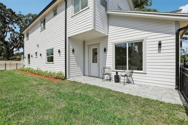 back of house with a patio and a lawn