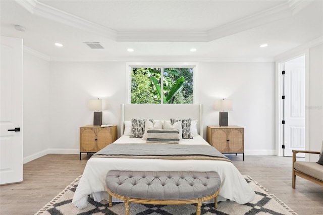 bedroom featuring light wood-type flooring, crown molding, and a raised ceiling