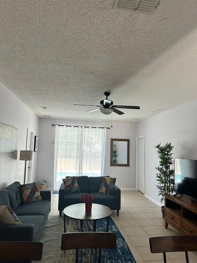 living room with a textured ceiling, ceiling fan, and light tile patterned floors