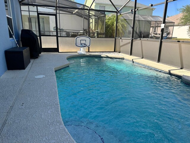 view of pool with glass enclosure and a patio area