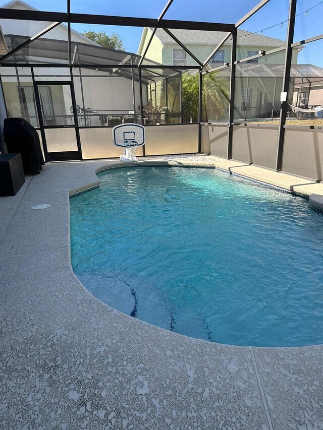 view of swimming pool featuring glass enclosure and a patio