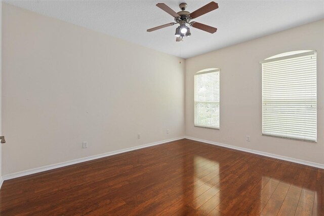 empty room with ceiling fan and dark hardwood / wood-style flooring