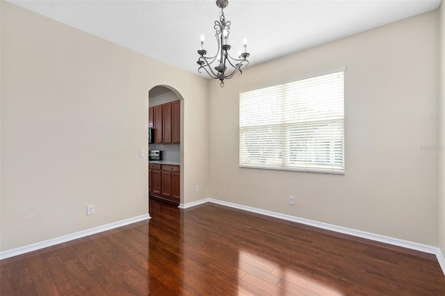 unfurnished room with an inviting chandelier and dark hardwood / wood-style floors