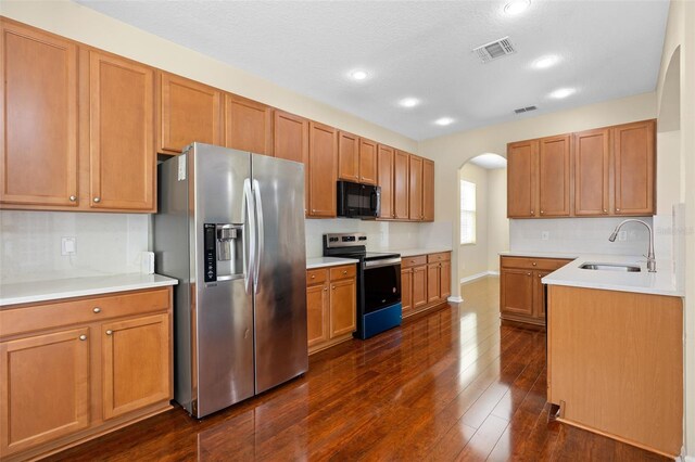 kitchen featuring sink, appliances with stainless steel finishes, a textured ceiling, and dark hardwood / wood-style flooring