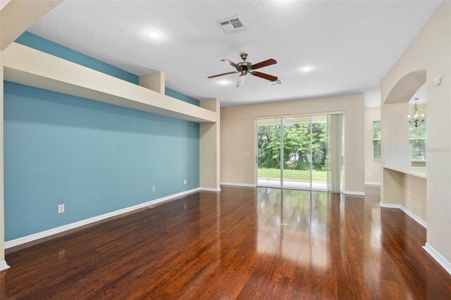 unfurnished living room featuring a textured ceiling, ceiling fan with notable chandelier, and dark hardwood / wood-style flooring