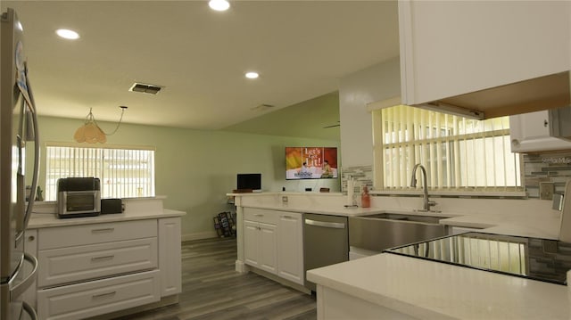 kitchen featuring white cabinets, kitchen peninsula, stainless steel appliances, and backsplash