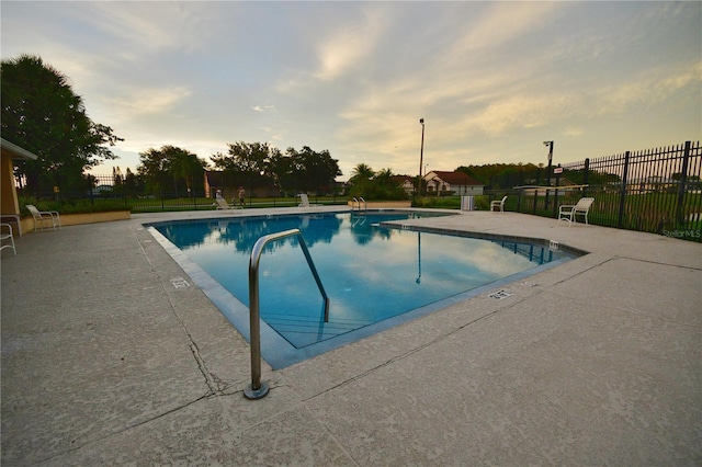 pool at dusk featuring a patio area