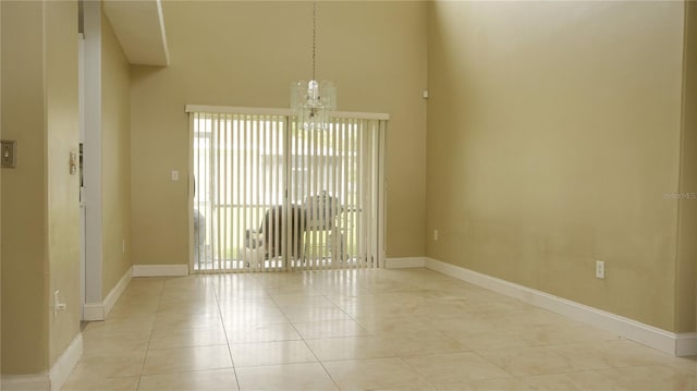 spare room featuring an inviting chandelier, a high ceiling, and light tile patterned floors