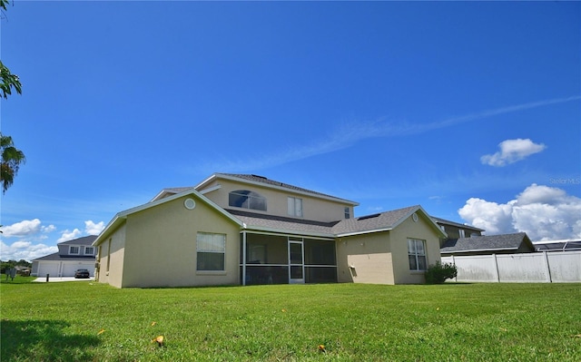 rear view of house featuring a sunroom and a lawn