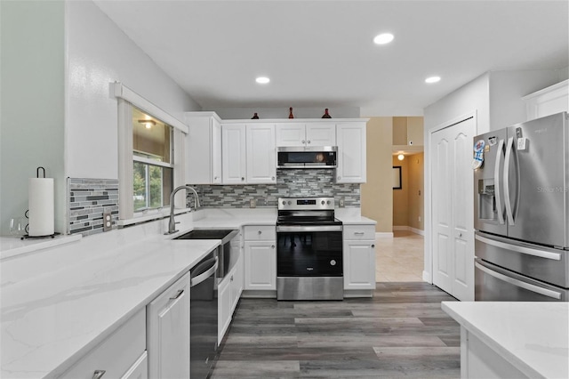 kitchen featuring white cabinetry, stainless steel appliances, light stone countertops, sink, and decorative backsplash