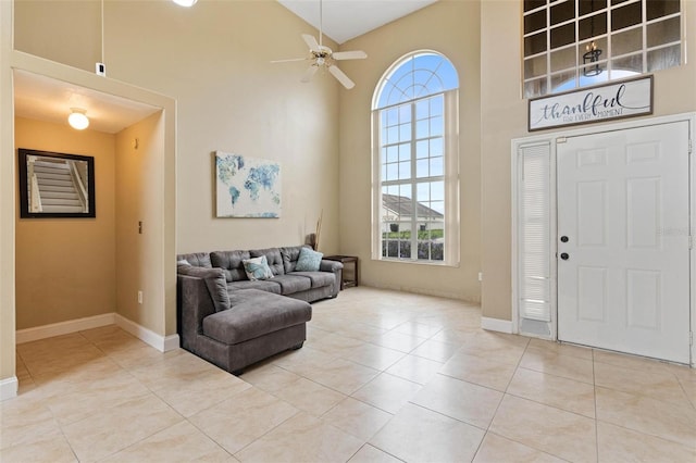 entrance foyer with ceiling fan, a towering ceiling, a healthy amount of sunlight, and light tile patterned floors