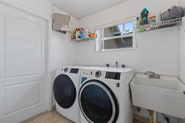 laundry area featuring washing machine and dryer, sink, and light tile patterned floors