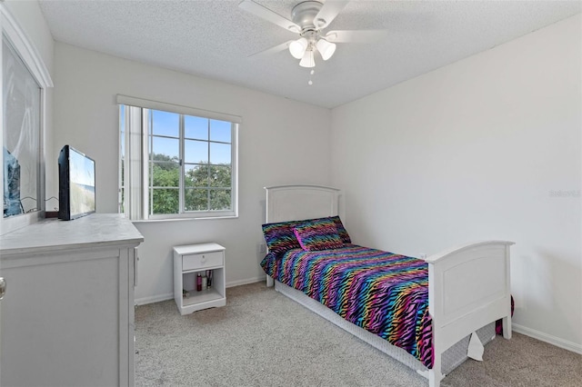 bedroom featuring ceiling fan, light carpet, and a textured ceiling