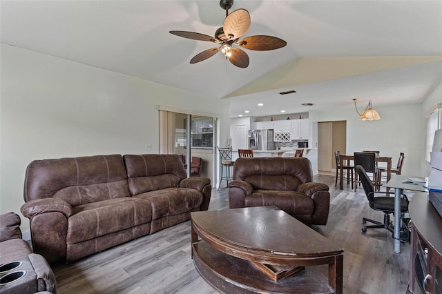 living room featuring light hardwood / wood-style floors, lofted ceiling, and ceiling fan