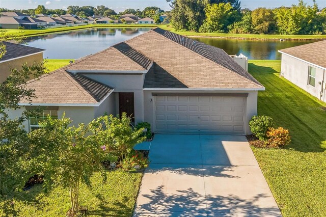 view of front of home with a garage, a water view, and a front lawn