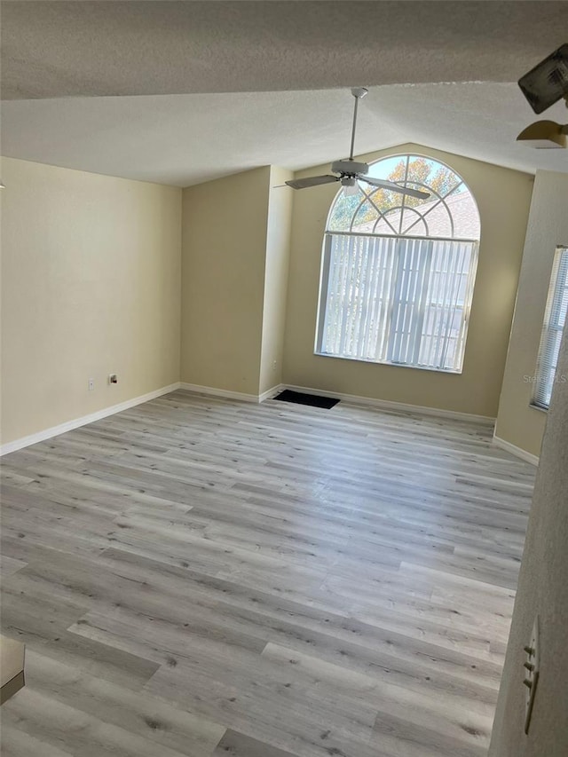 unfurnished room with vaulted ceiling, a textured ceiling, light hardwood / wood-style flooring, and ceiling fan