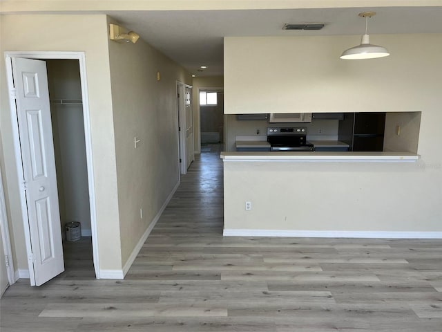 kitchen with black appliances, kitchen peninsula, hanging light fixtures, and light hardwood / wood-style floors