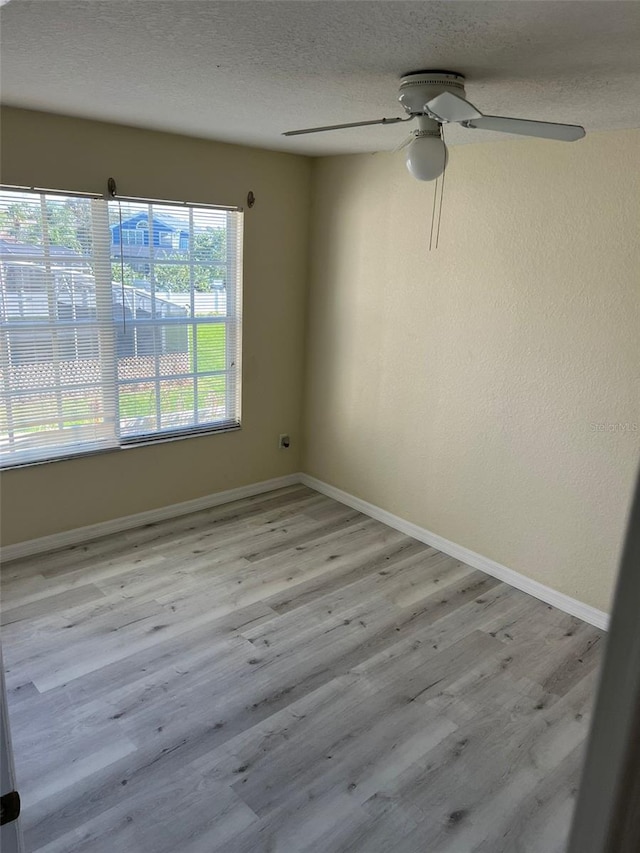 empty room with ceiling fan, a textured ceiling, and light hardwood / wood-style flooring