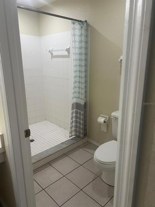 bathroom with toilet, a shower with shower curtain, and tile patterned flooring