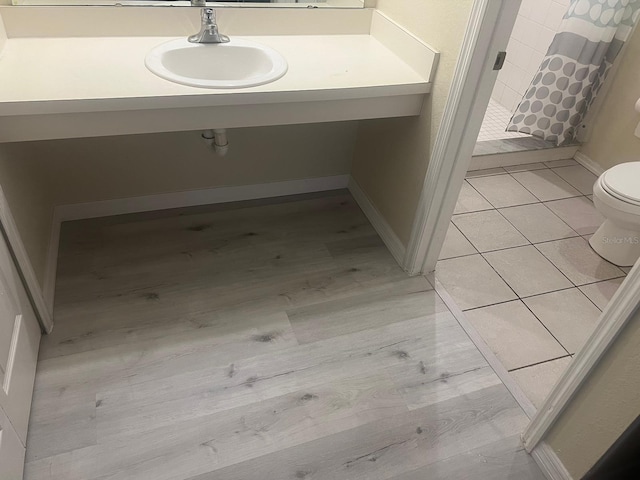 bathroom featuring toilet, a shower with shower curtain, sink, and tile patterned flooring