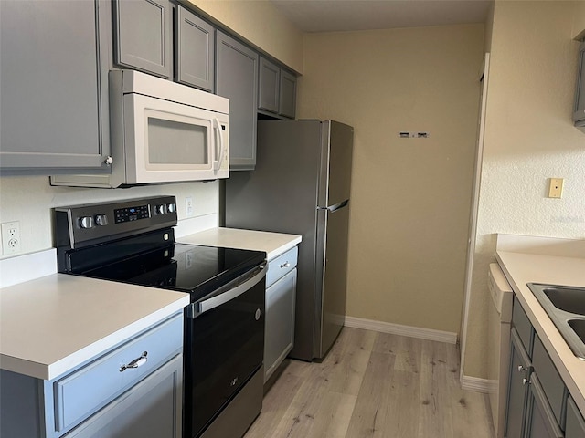 kitchen featuring appliances with stainless steel finishes, gray cabinetry, and light hardwood / wood-style flooring