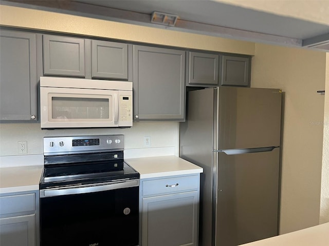 kitchen with gray cabinetry and appliances with stainless steel finishes