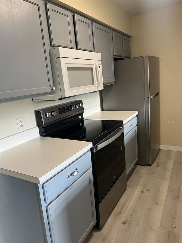 kitchen with gray cabinetry, black / electric stove, and light hardwood / wood-style flooring